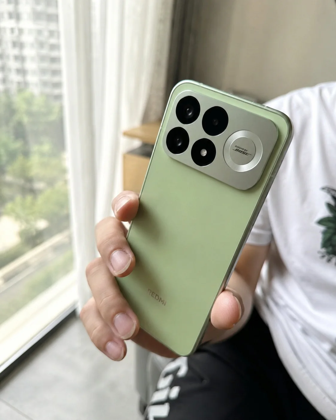 REDMI K100 Pro in mint green held near a window